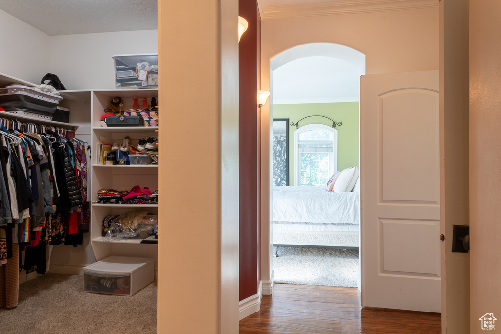 Spacious closet with arched walkways and wood finished floors