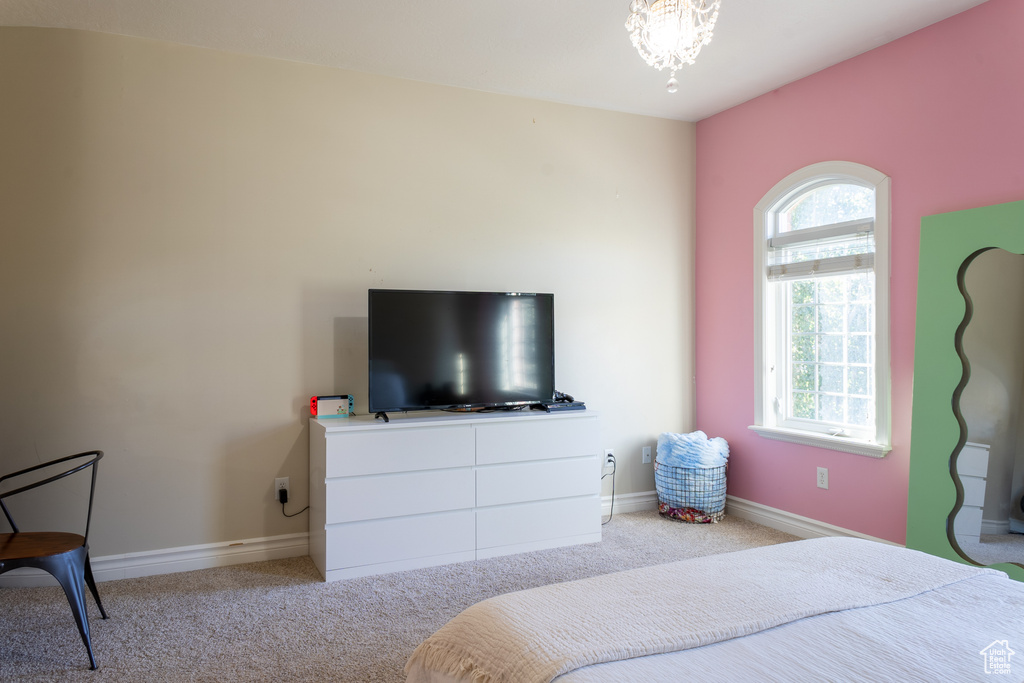 Carpeted bedroom with baseboards and a chandelier