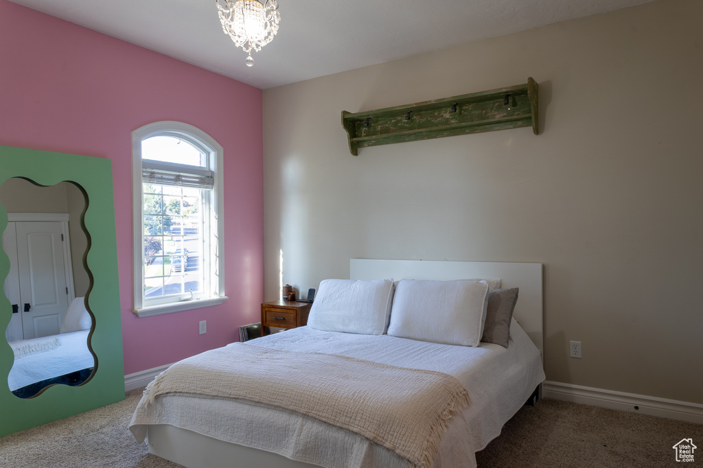 Carpeted bedroom featuring a chandelier and baseboards
