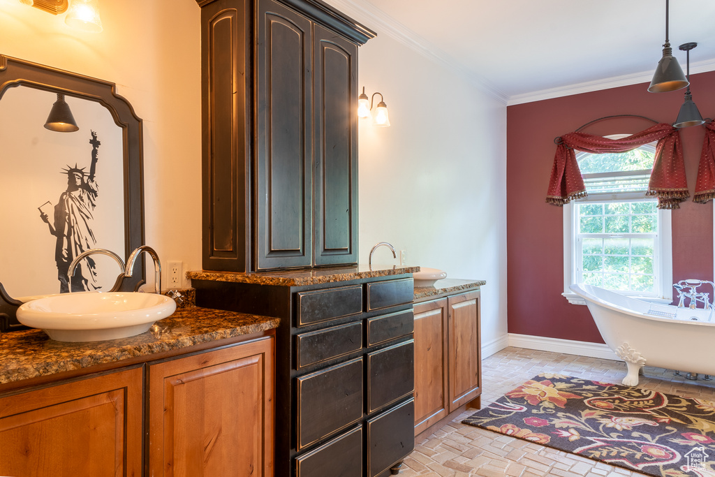 Bathroom with vanity, a freestanding tub, ornamental molding, baseboards, and brick patterned floors