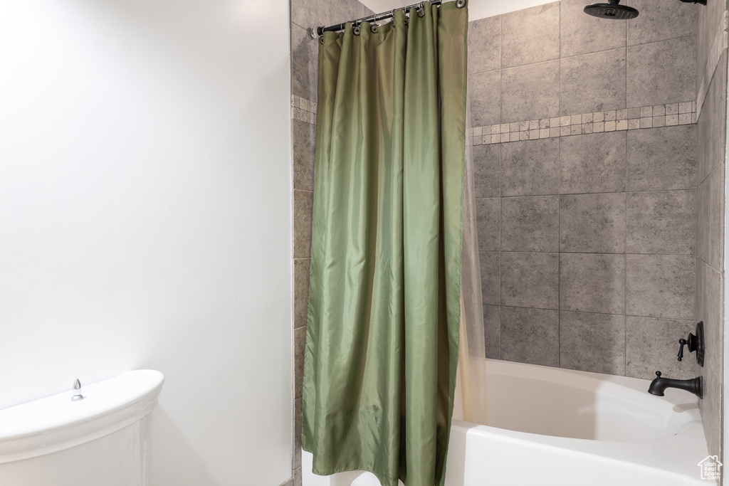 Full bathroom featuring shower / bathtub combination with curtain and toilet