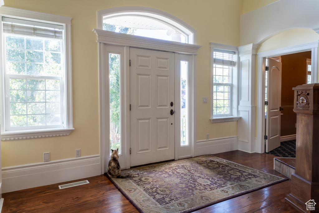 Foyer featuring wood finished floors and decorative columns