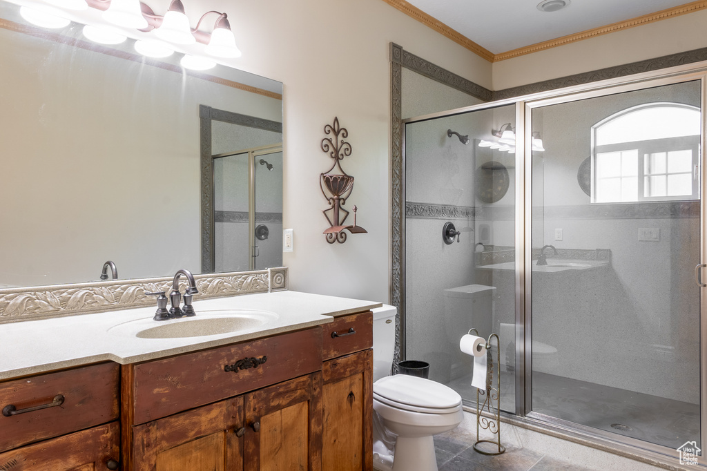 Bathroom featuring a shower stall, vanity, toilet, ornamental molding, and tile patterned floors