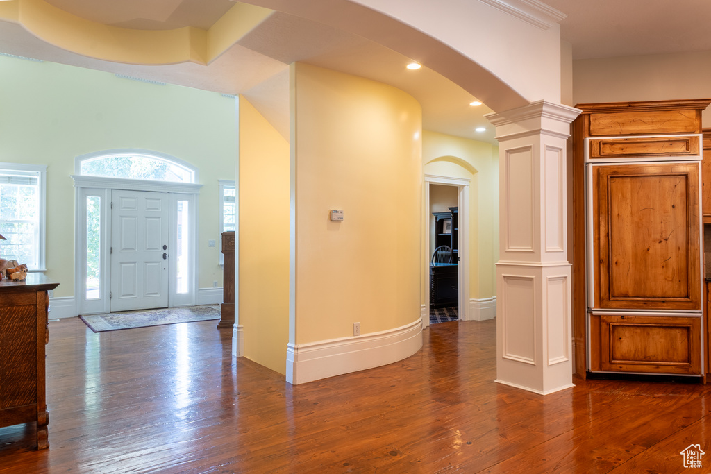 Foyer with arched walkways, dark wood-style flooring, ornate columns, recessed lighting, and baseboards