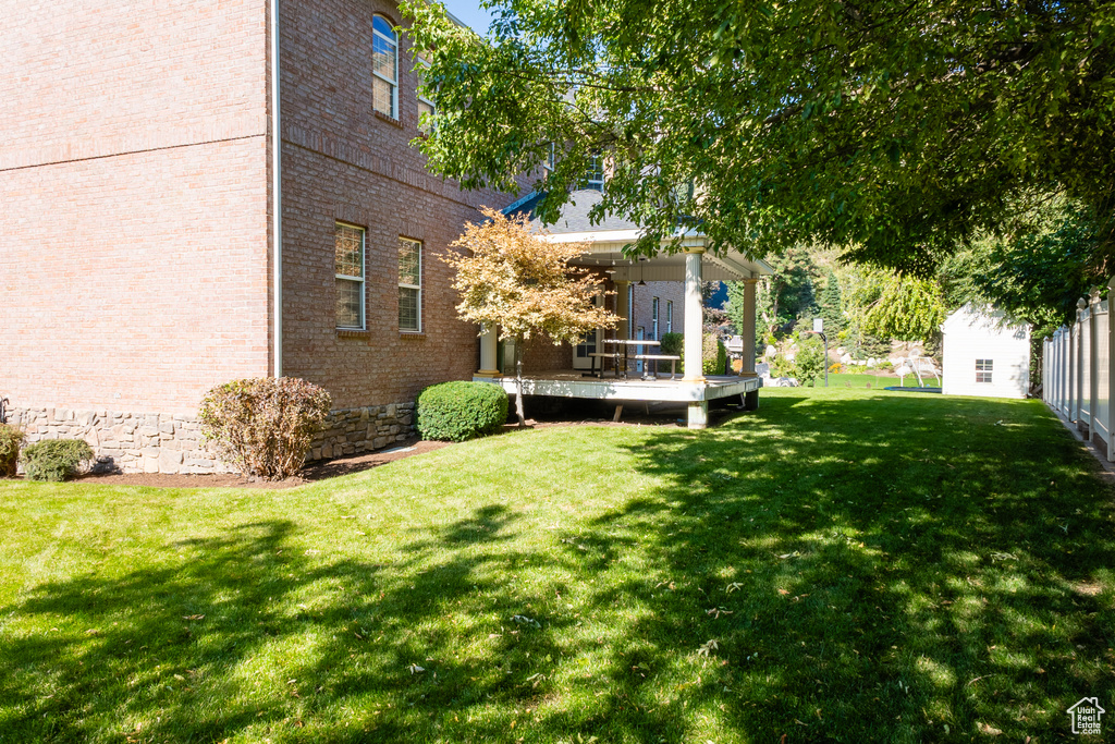 View of grassy yard featuring a deck
