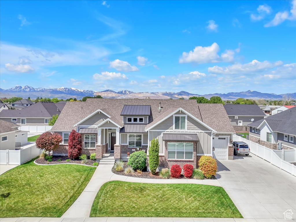 Craftsman-style house featuring board and batten siding, driveway, a standing seam roof, and a mountain view
