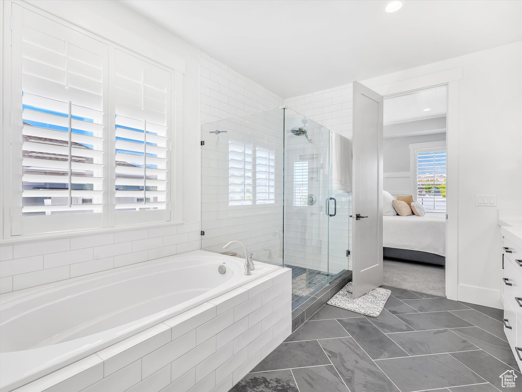 Ensuite bathroom with a stall shower, a bath, vanity, and marble look tiles