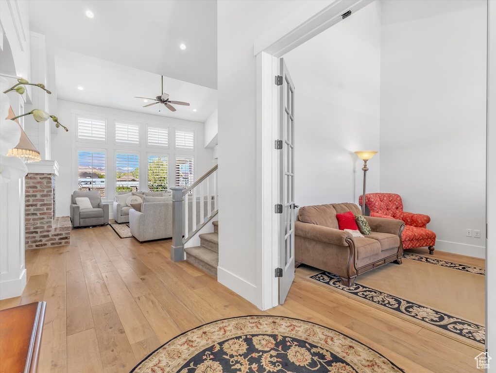 Living room featuring light wood-type flooring, ceiling fan, stairway, baseboards, and recessed lighting