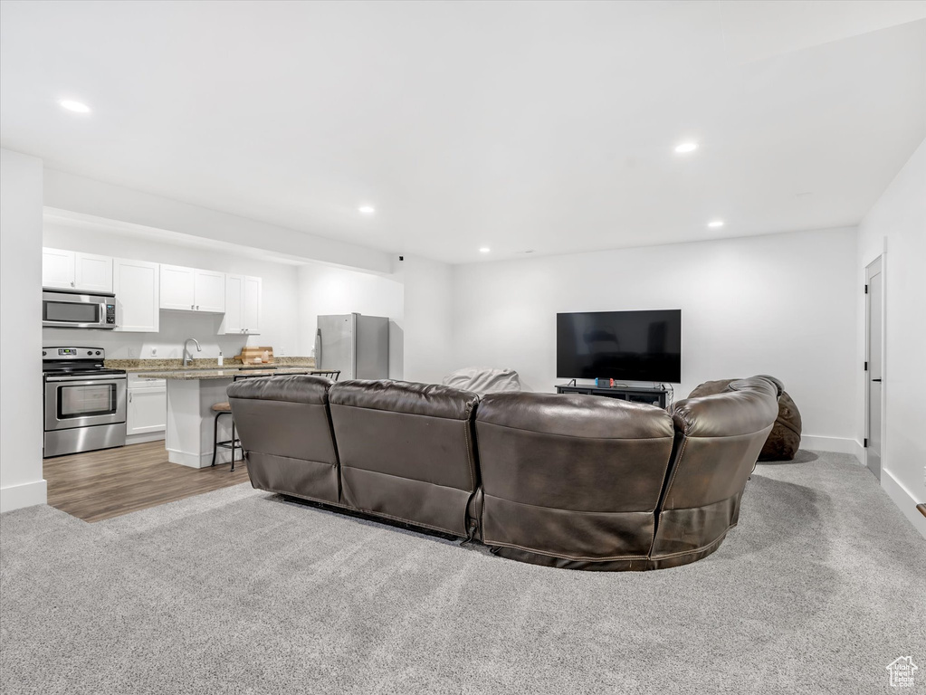 Living area featuring recessed lighting, light carpet, and baseboards