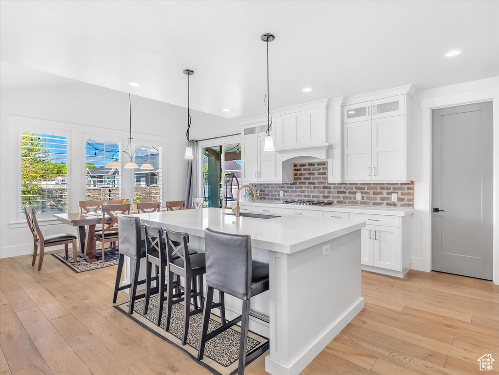 Kitchen featuring a sink, light countertops, stainless steel gas stovetop, light wood finished floors, and recessed lighting