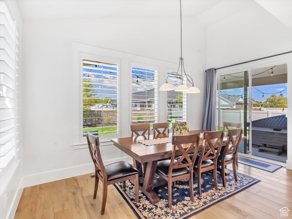 Dining space with light wood finished floors, baseboards, and vaulted ceiling