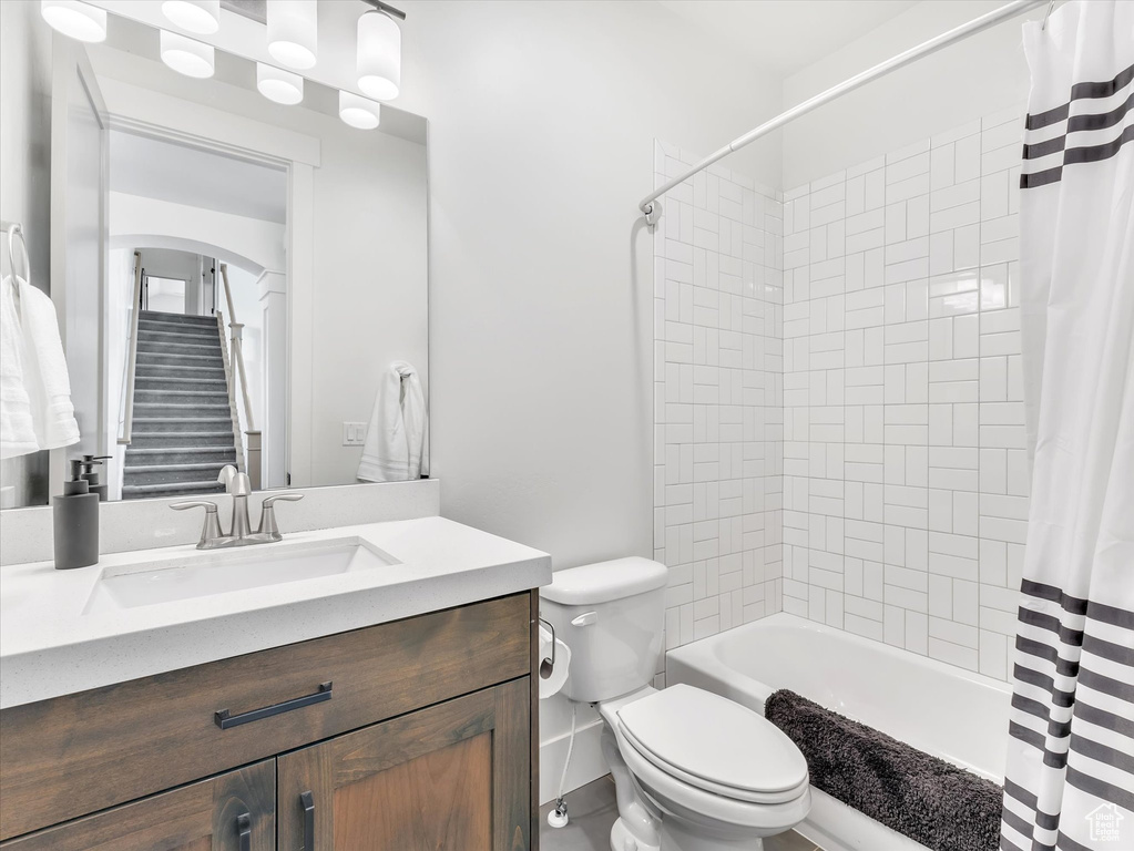 Bathroom with toilet, vanity, and shower / tub combo with curtain