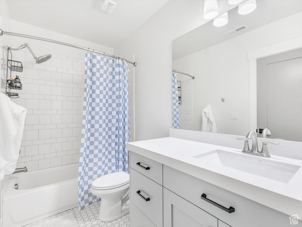 Full bathroom featuring toilet, vanity, shower / bath combo, and tile patterned floors