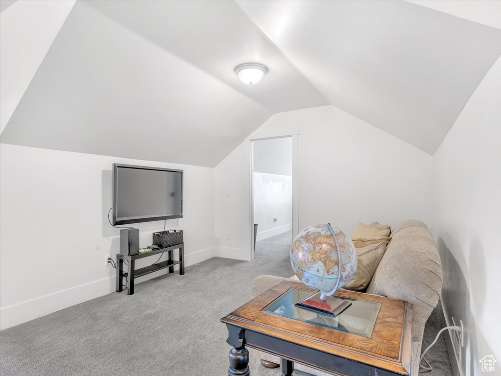 Carpeted living area featuring lofted ceiling and baseboards