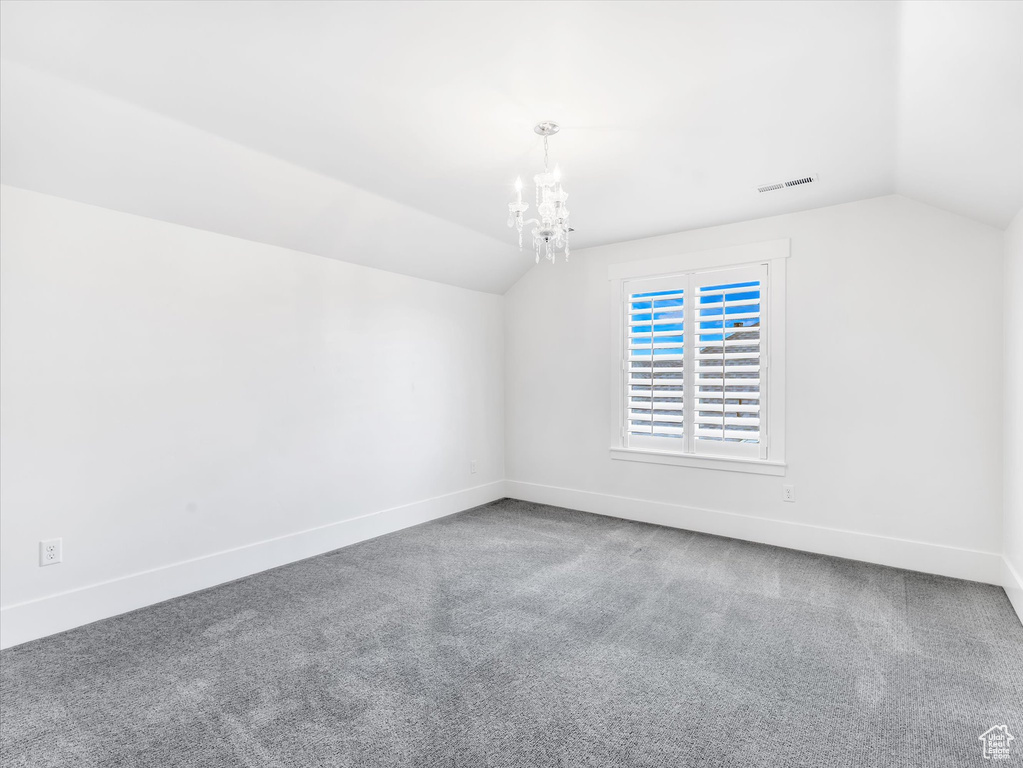 Unfurnished room with vaulted ceiling, baseboards, a chandelier, and carpet flooring