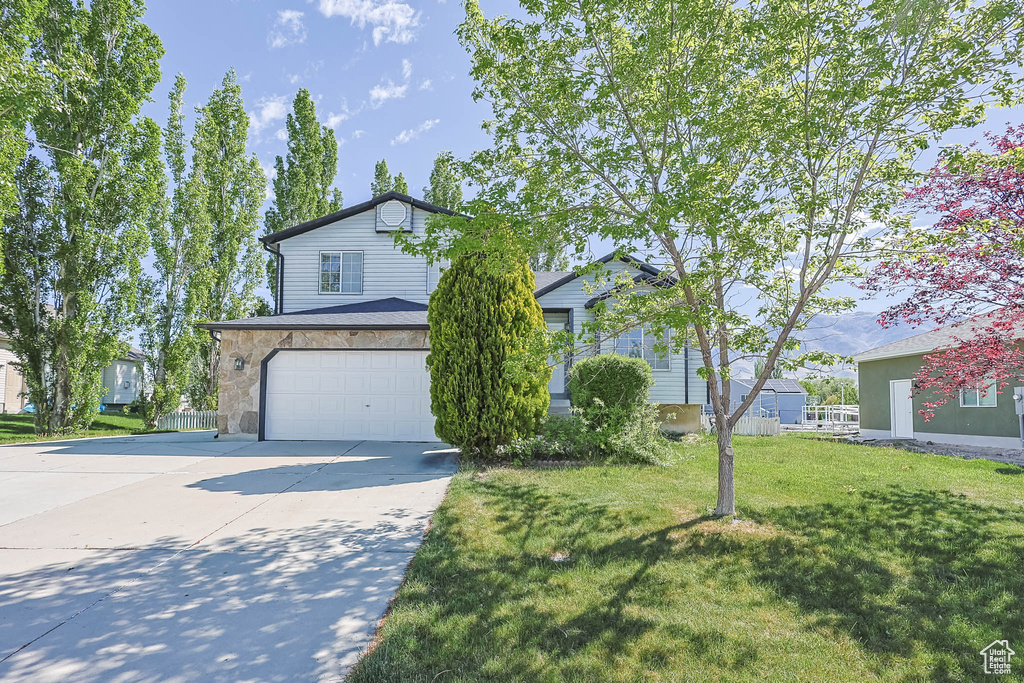 View of front of property with a garage, concrete driveway, and a front yard