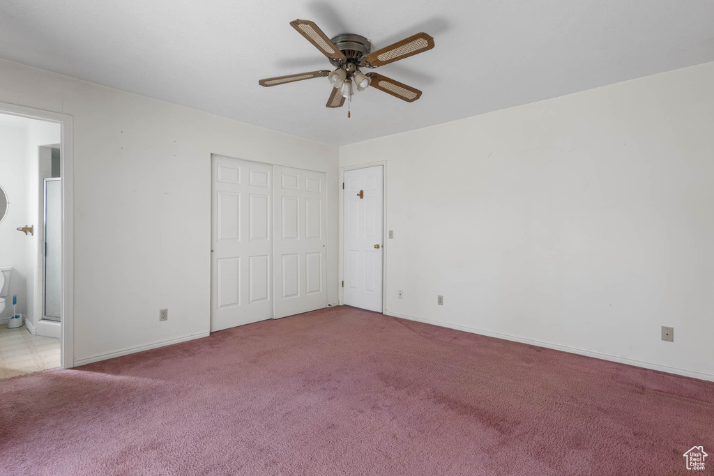 Unfurnished bedroom featuring carpet flooring, connected bathroom, baseboards, ceiling fan, and a closet