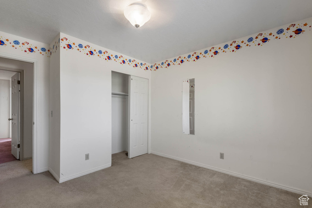 Unfurnished bedroom featuring light carpet, baseboards, and a closet