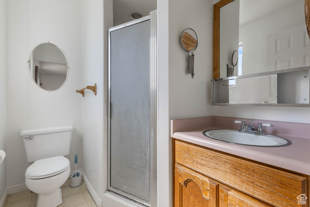 Full bathroom with a sink, a shower stall, toilet, and baseboards