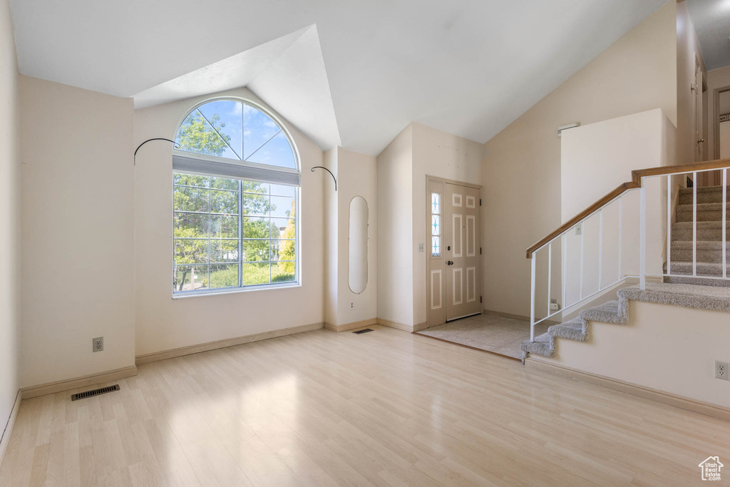 Foyer entrance with vaulted ceiling, wood finished floors, plenty of natural light, stairs, and baseboards