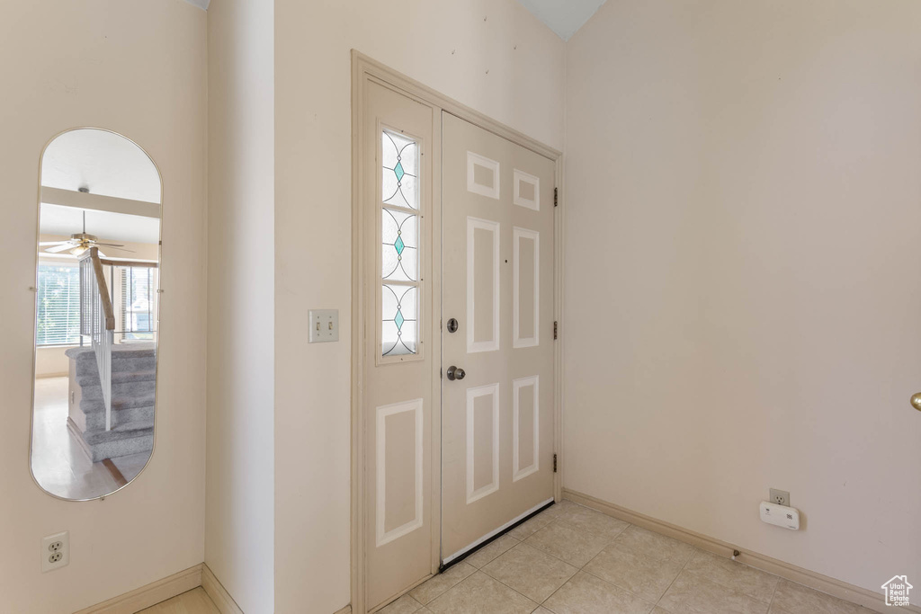 Entryway featuring baseboards, ceiling fan, and light tile patterned floors