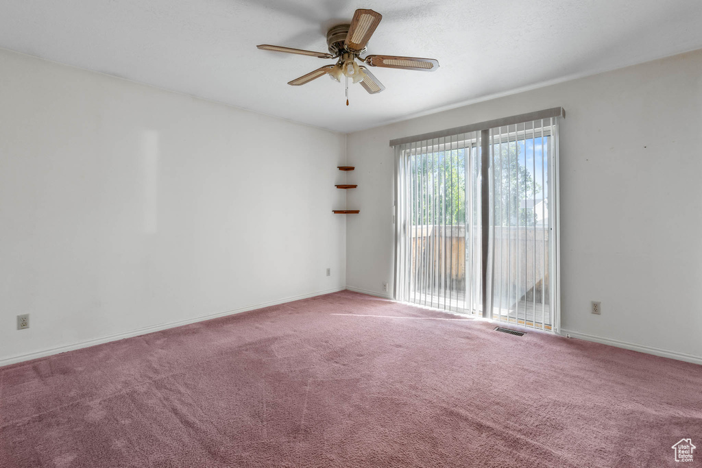 Carpeted spare room featuring a ceiling fan and baseboards