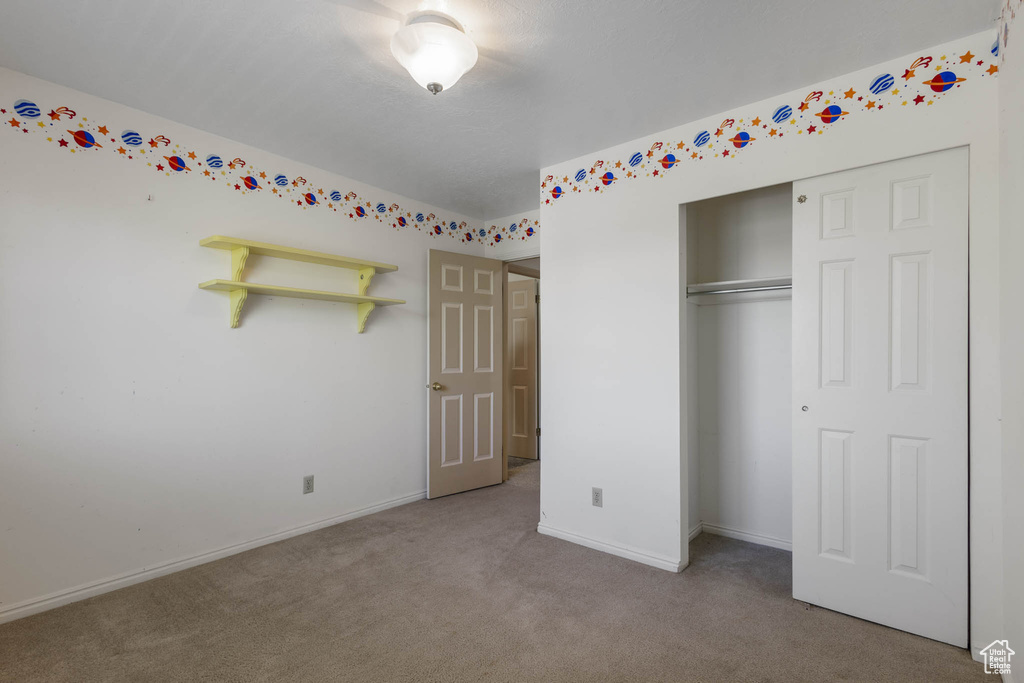 Unfurnished bedroom featuring carpet, a closet, and baseboards