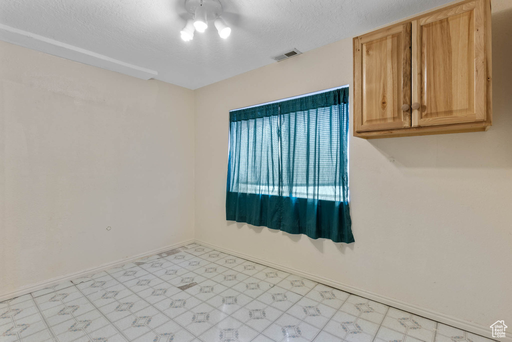 Unfurnished room with light flooring, baseboards, and a textured ceiling