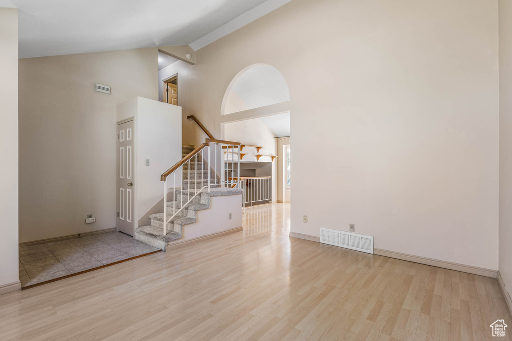 Interior space with wood finished floors, stairway, high vaulted ceiling, and baseboards