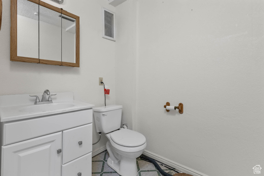 Bathroom with toilet, vanity, tile patterned flooring, and baseboards