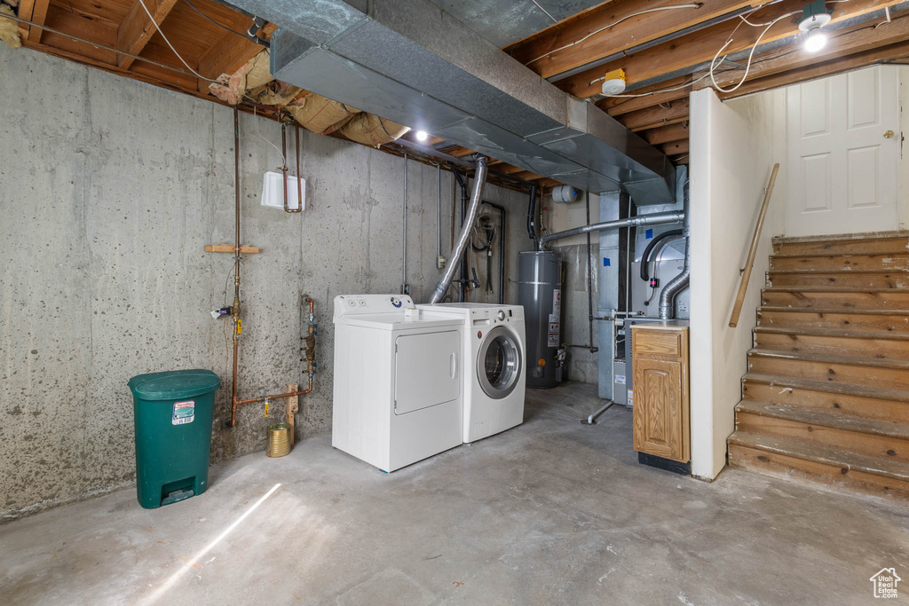 Unfinished below grade area featuring water heater, independent washer and dryer, heating unit, and stairway