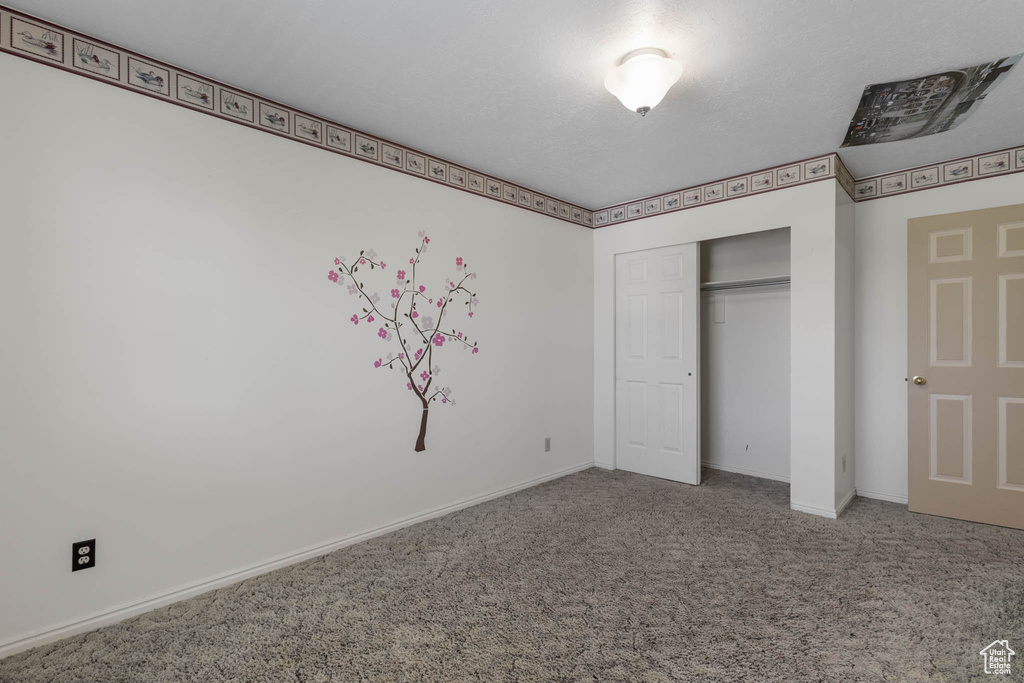 Unfurnished bedroom featuring carpet flooring, baseboards, and a closet