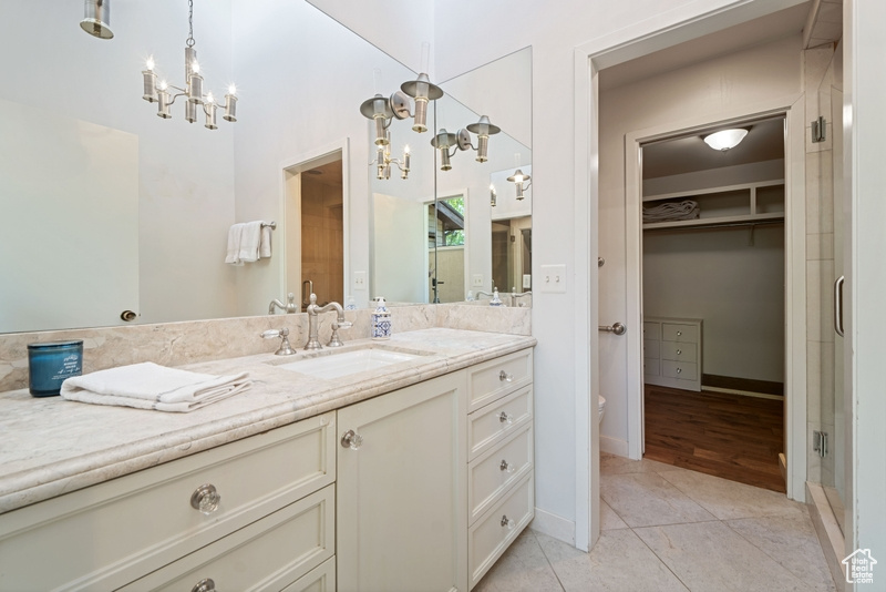 Bathroom featuring a chandelier, tile patterned flooring, vanity, and baseboards