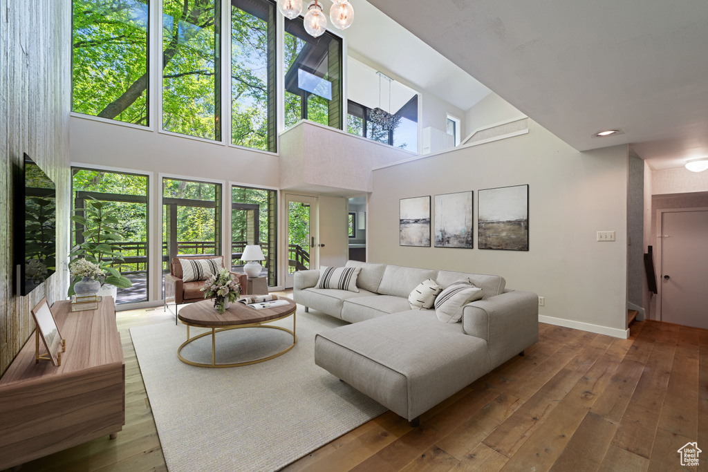 Living area featuring wood-type flooring, baseboards, healthy amount of natural light, and a towering ceiling