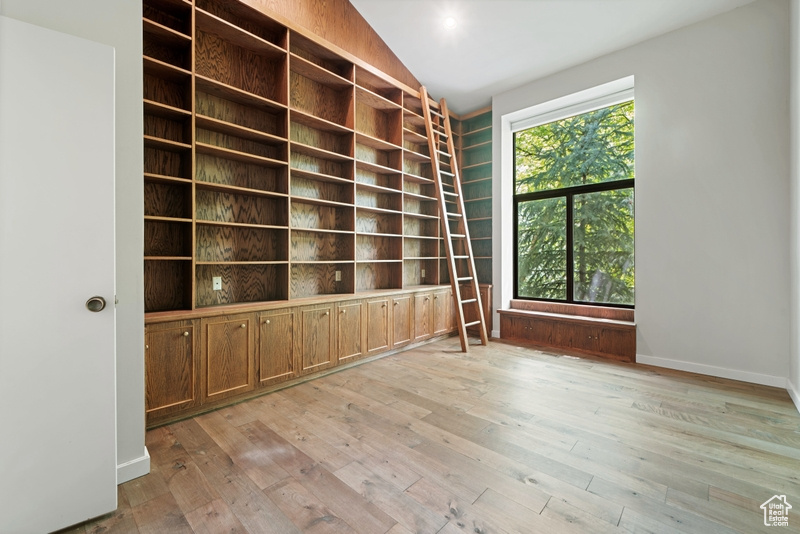 Spare room with light wood-type flooring, vaulted ceiling, baseboards, and built in features