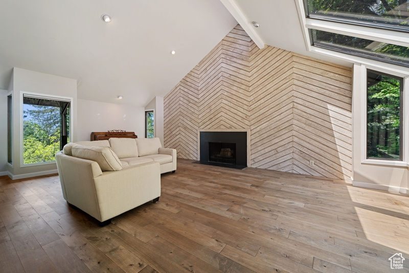 Living area with an accent wall, healthy amount of natural light, and hardwood / wood-style floors