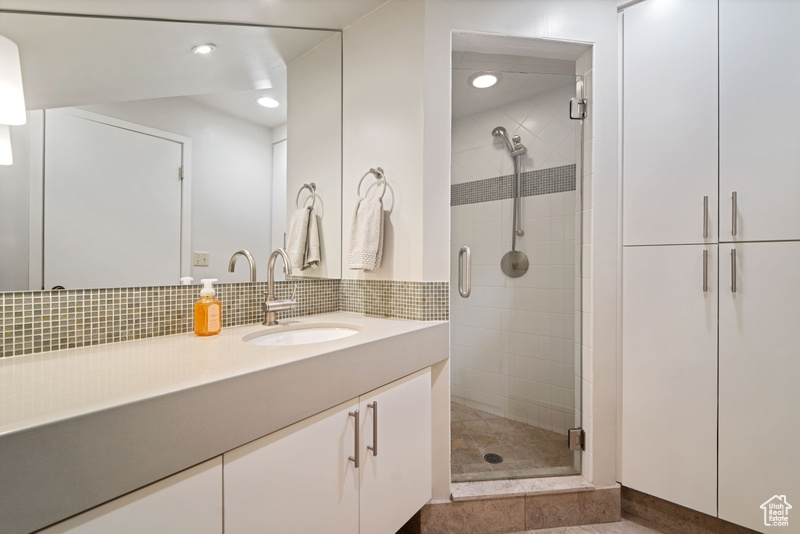 Bathroom featuring a shower stall, vanity, decorative backsplash, and recessed lighting
