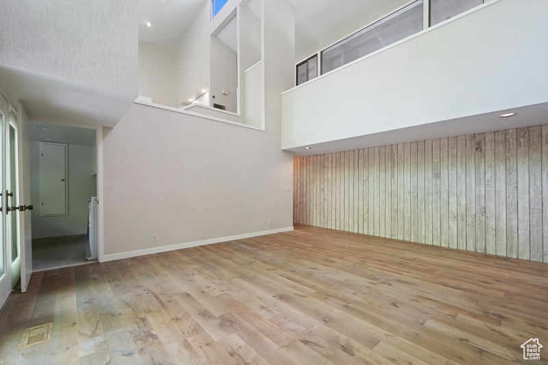 Unfurnished living room with a towering ceiling, hardwood / wood-style flooring, and baseboards