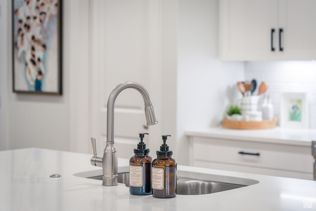 Kitchen view of light countertops, white cabinets, and a sink