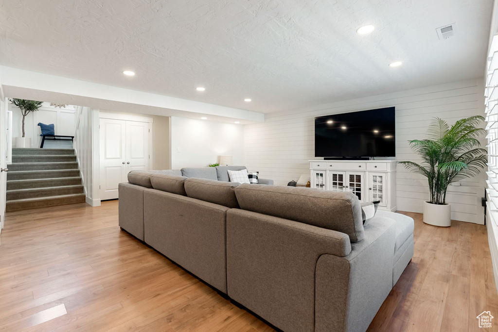 Living area with stairway, light wood-type flooring, recessed lighting, and wood walls