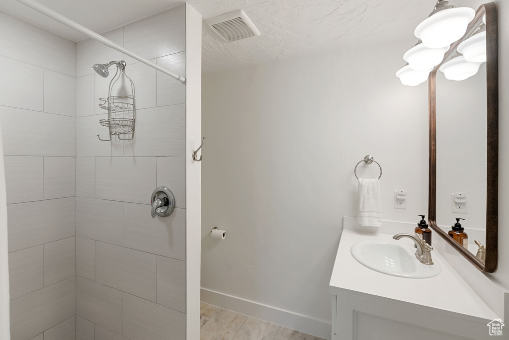 Bathroom with vanity, tiled shower, and baseboards
