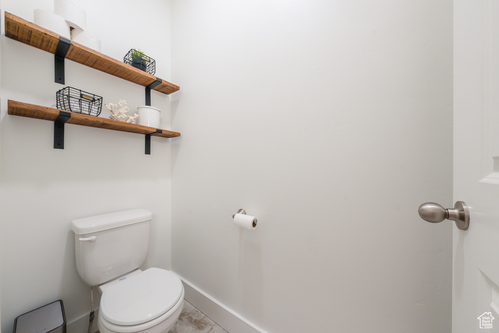 Bathroom featuring baseboards, toilet, and marble finish floors