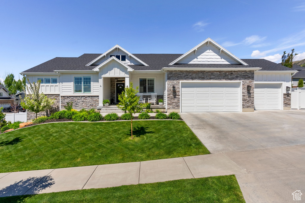 Craftsman house with stone siding, board and batten siding, an attached garage, and driveway