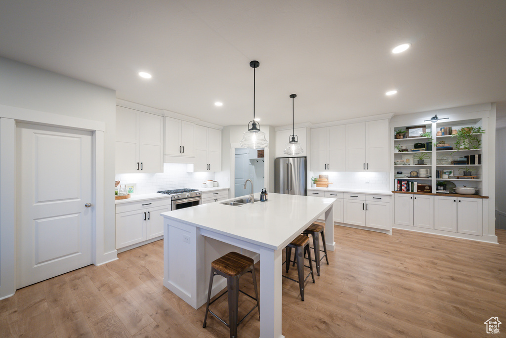 Kitchen with premium appliances, a sink, a kitchen breakfast bar, white cabinetry, and recessed lighting