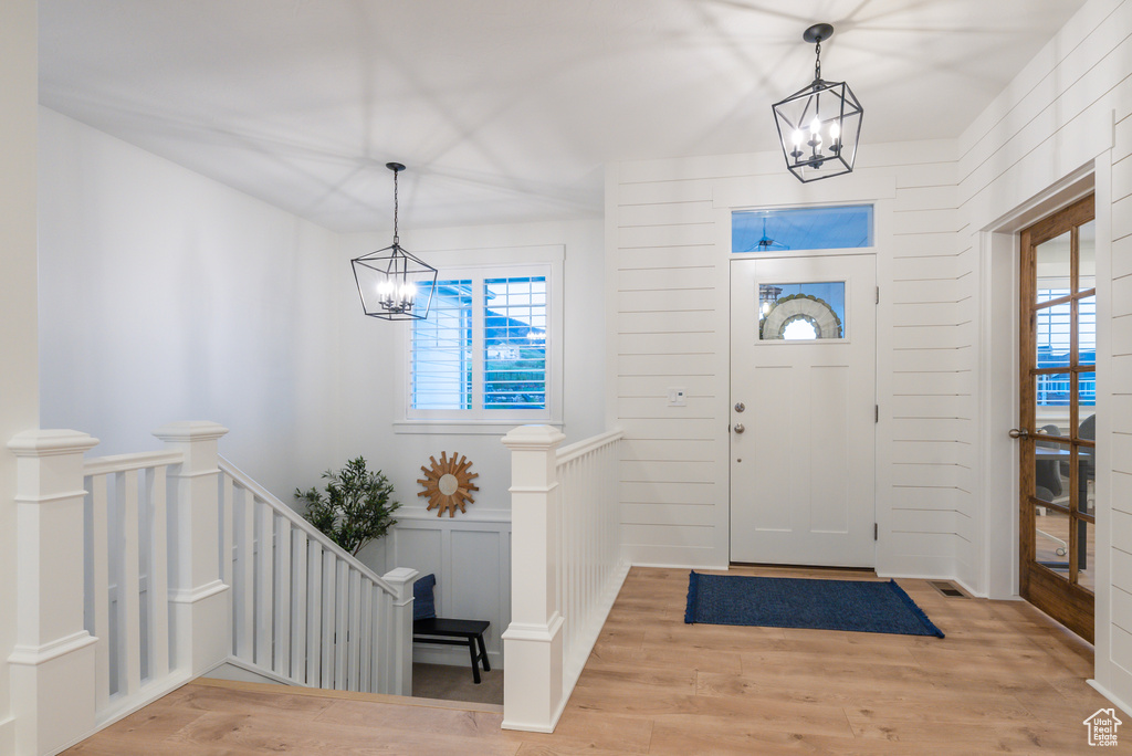 Foyer entrance with a chandelier, plenty of natural light, and light wood-style floors