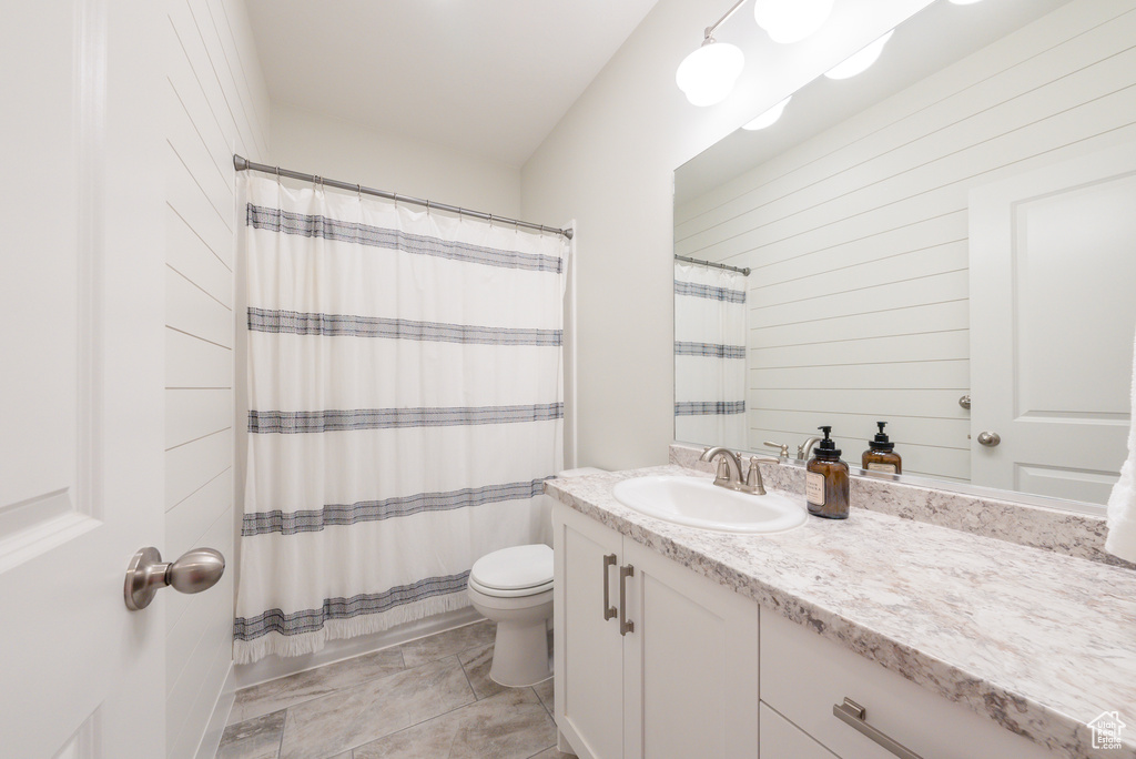 Bathroom featuring vanity, toilet, curtained shower, and wood walls