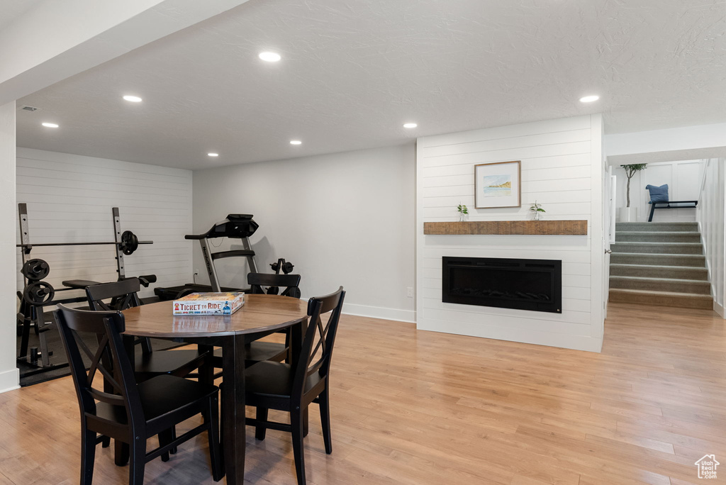 Dining room featuring baseboards, light wood-type flooring, recessed lighting, a fireplace, and stairway