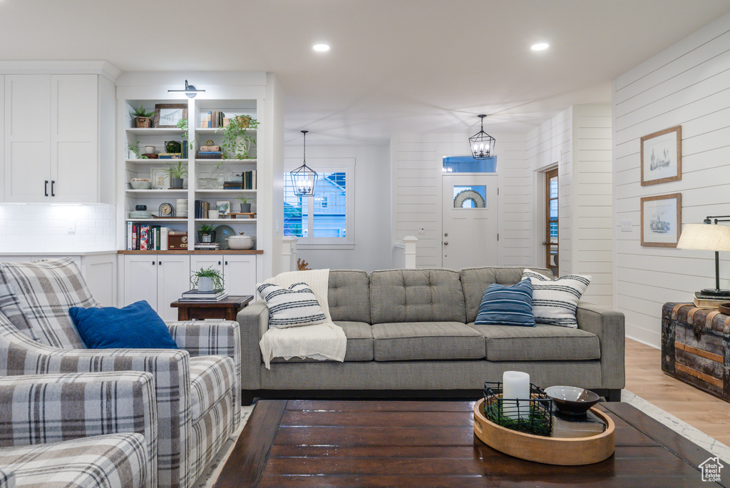 Living room featuring wood finished floors, recessed lighting, a chandelier, and wood walls