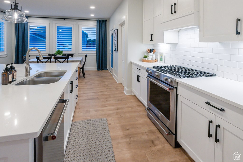 Kitchen featuring stainless steel appliances, a sink, backsplash, recessed lighting, and light countertops