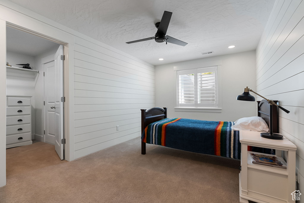 Bedroom featuring wood walls, carpet flooring, a textured ceiling, ceiling fan, and recessed lighting